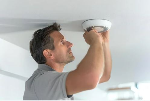 man fixing smoke alarm